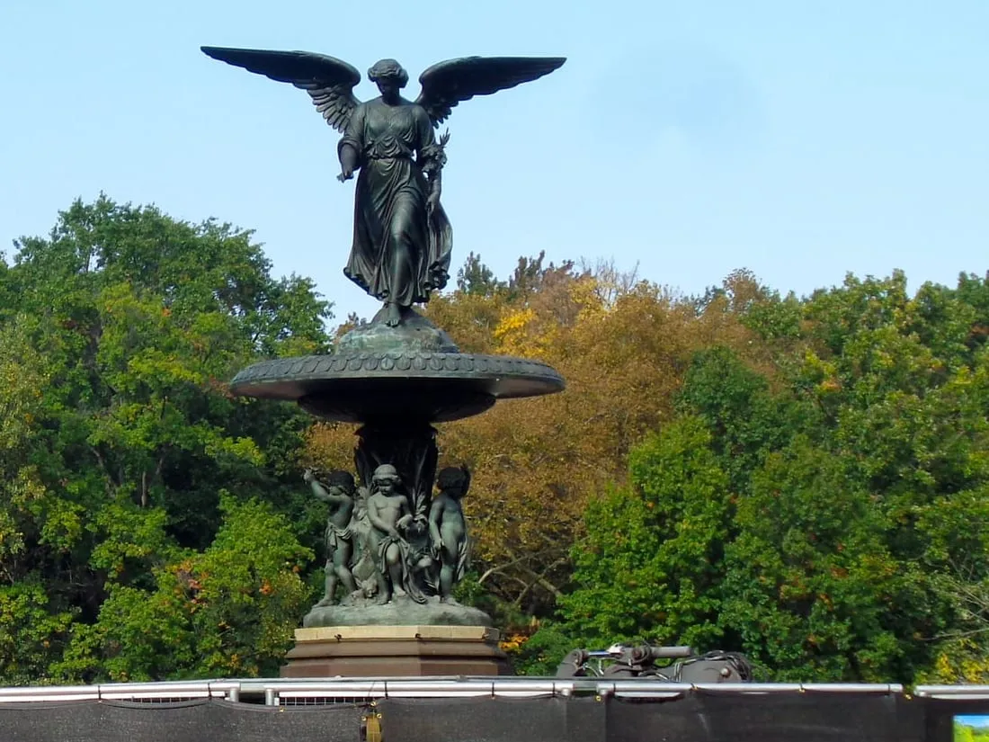 The Angel of the Waters atop Bethesda Fountain, rising above construction fencing and autumn trees