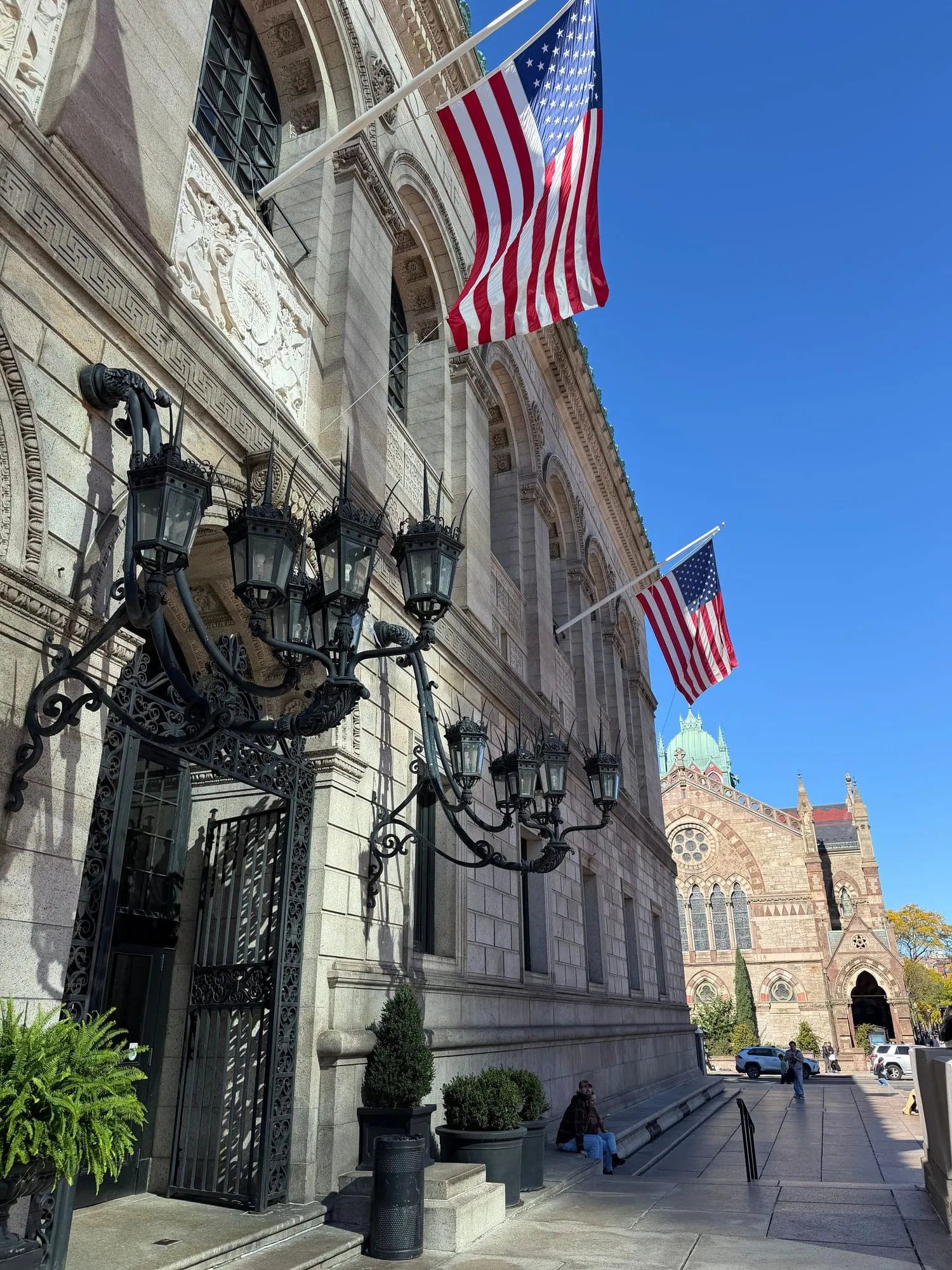 The grand stone entrance of the Boston Public Library, flags flying
