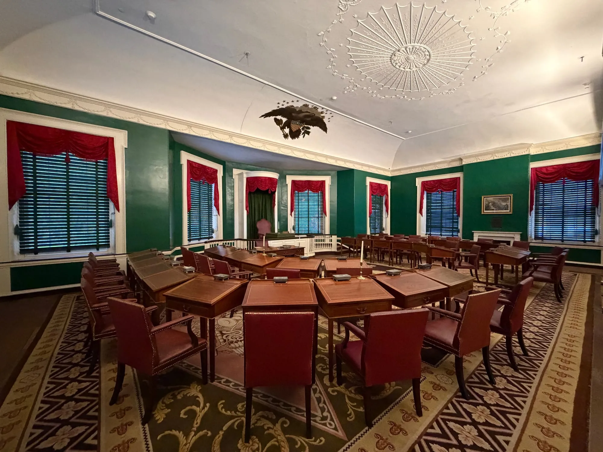 The Senate chamber in Congress Hall, with red chairs, green walls and a carved eagle