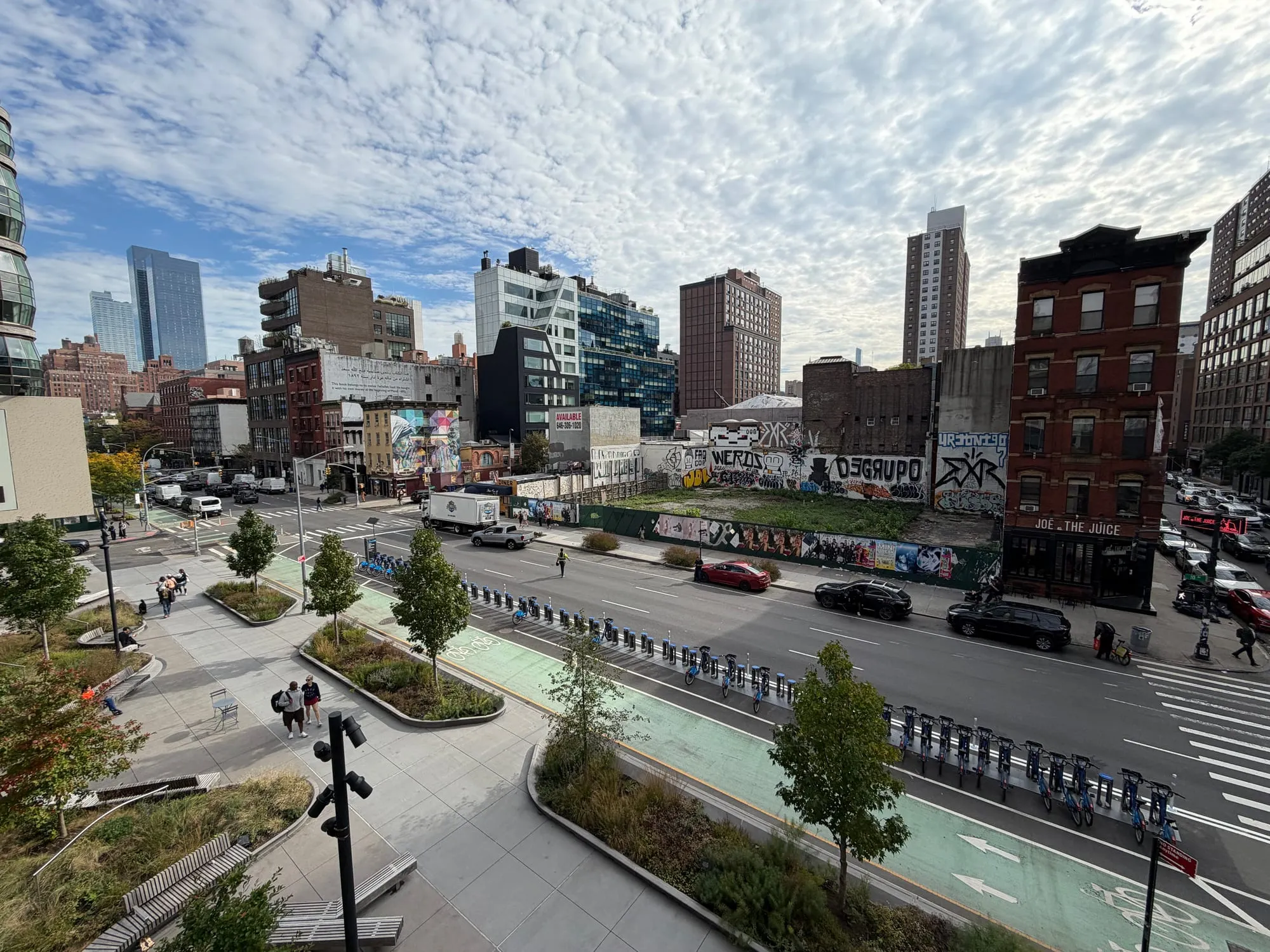 The High Line's planted walkway curving above a West Side street, with the city skyline beyond
