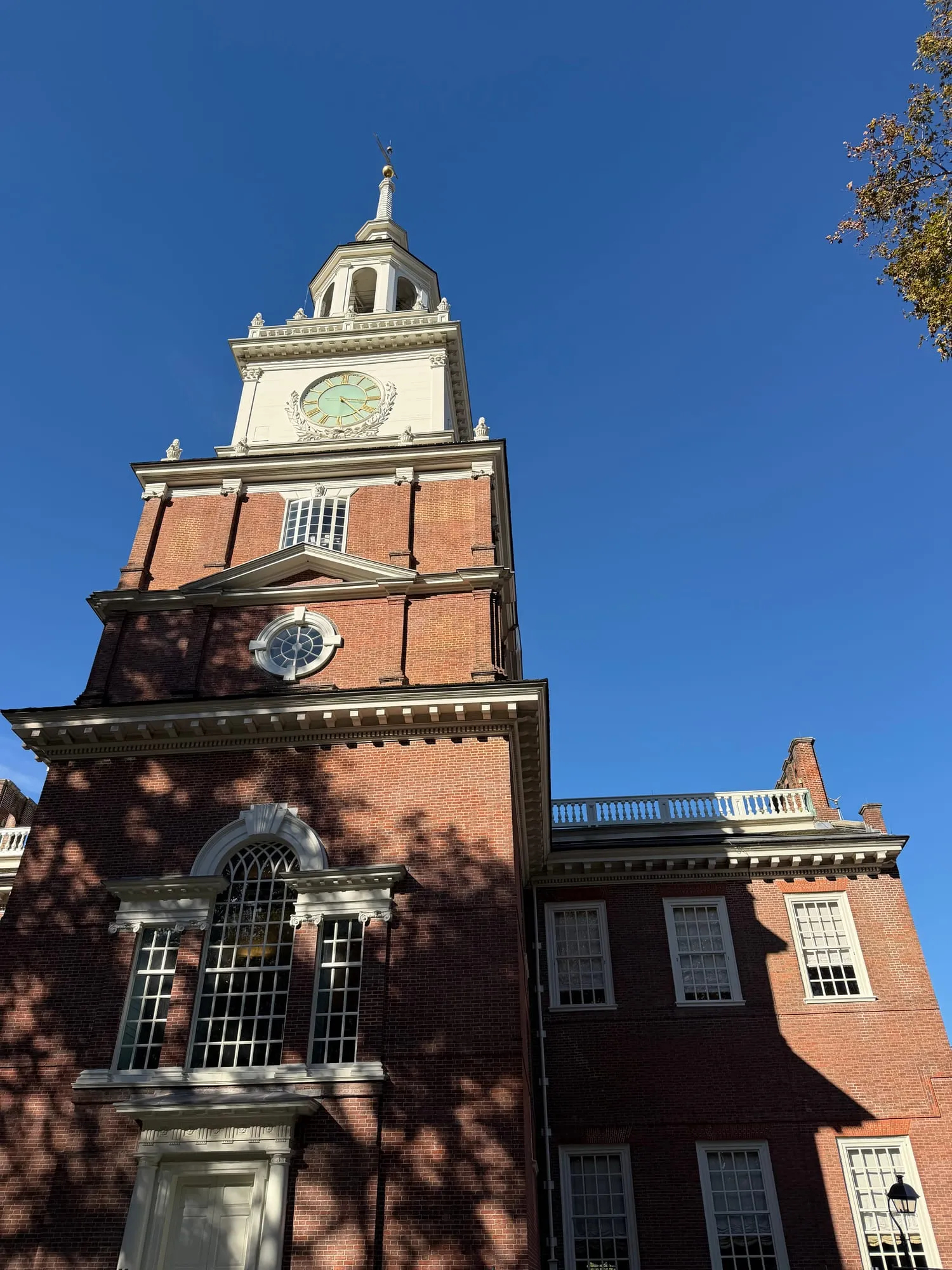 Independence Hall's red brick tower and white steeple against a deep blue sky