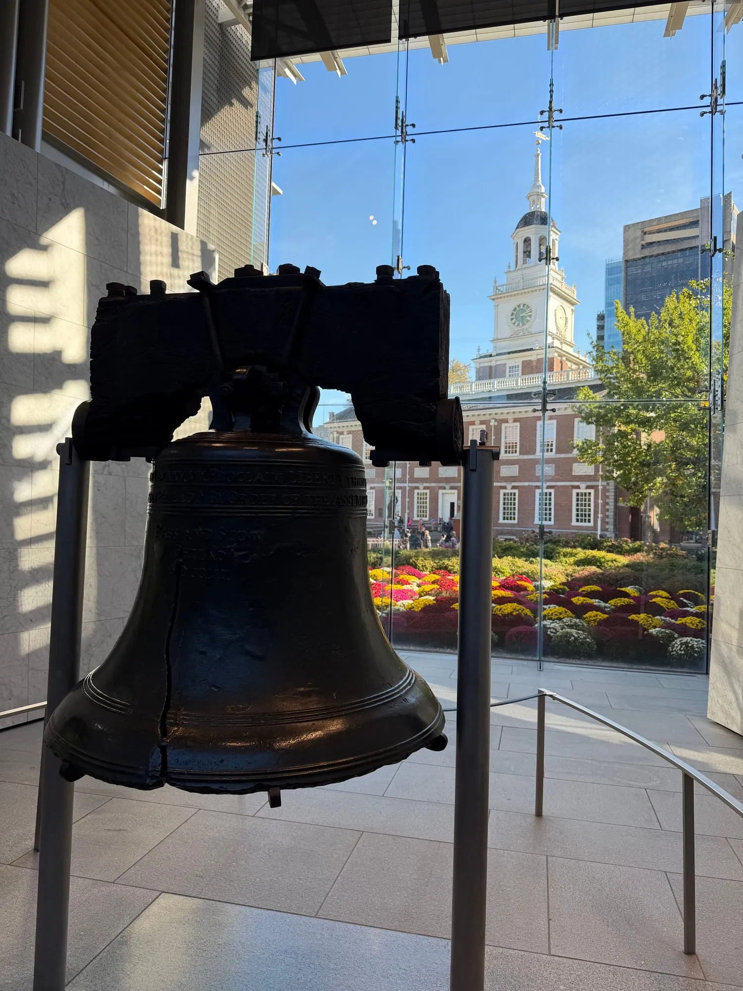 The Liberty Bell in its glass pavilion, with Independence Hall visible through the window
