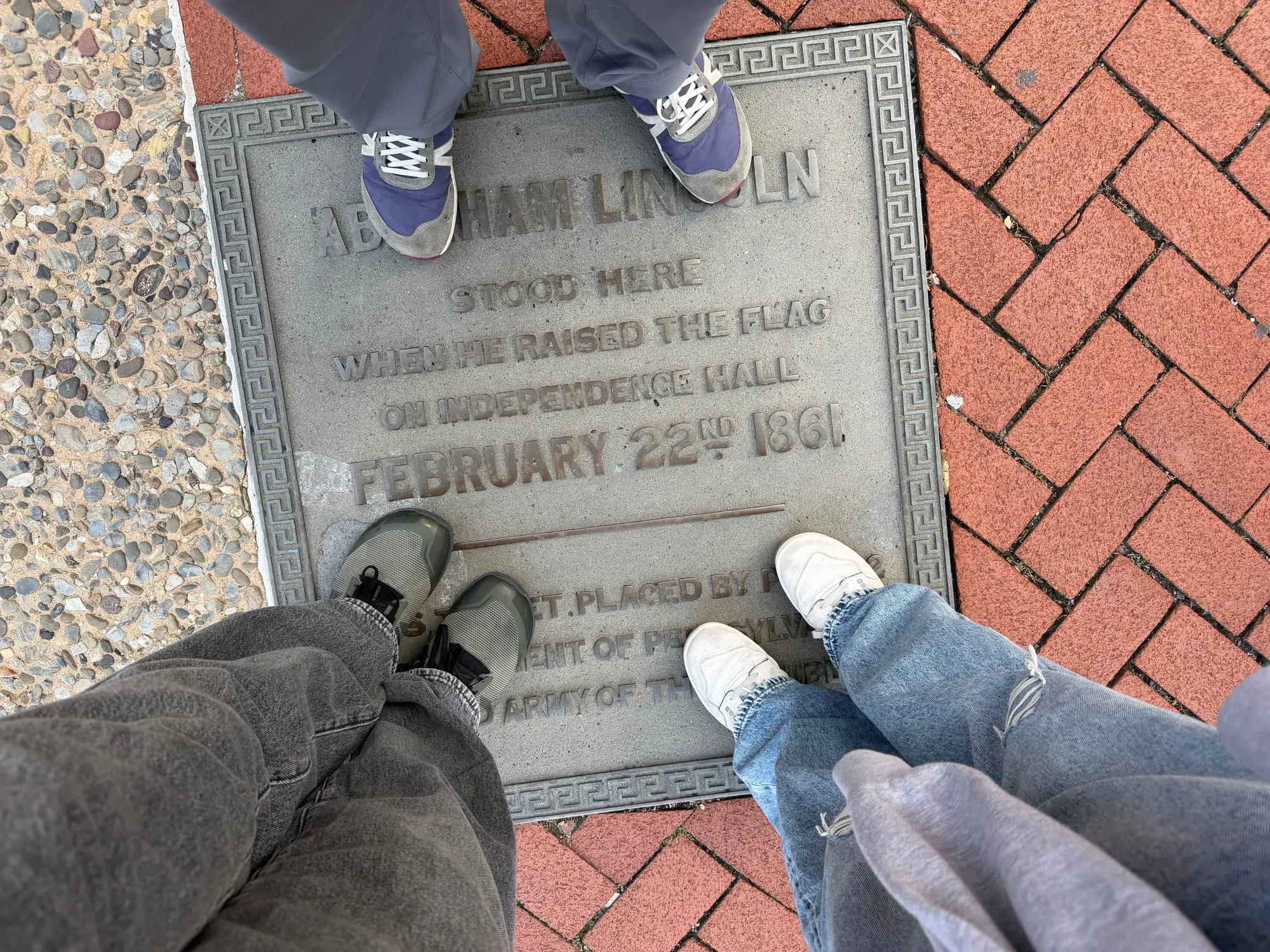 A plaque in the sidewalk marking where Abraham Lincoln stood to raise a flag in 1861, with feet on either side